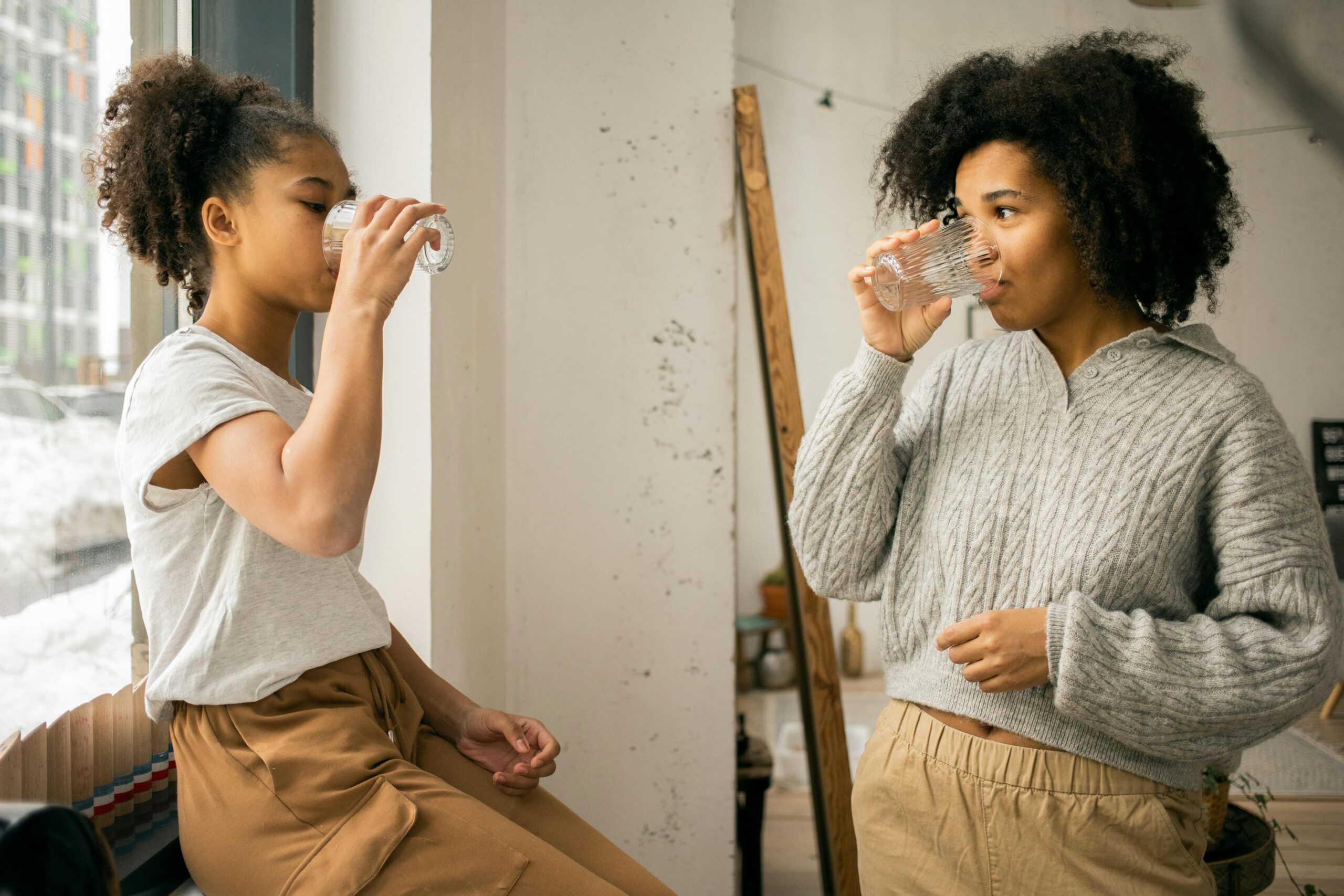 Two women drinking water from a glass